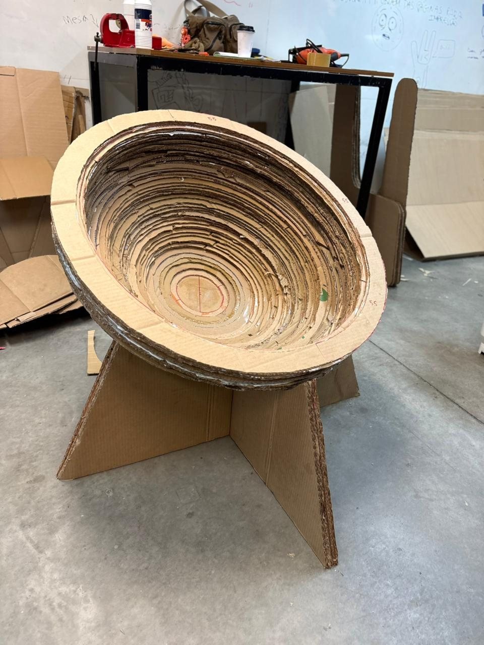 Cadeira Bowl em produção na oficina, cercada por chapas de papelão