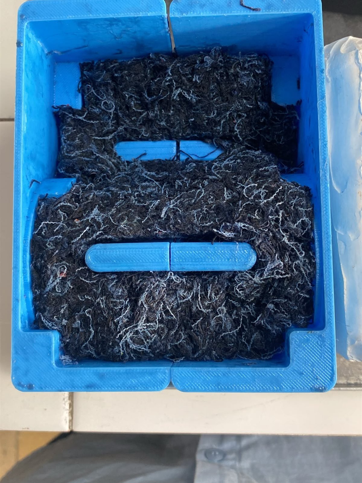 Fibra de jeans compactada dentro de molde azul impresso em 3D